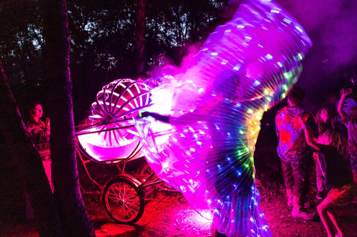 Nachtelijke parade-act met verlichte LED-vleugels en een versierde bakfiets